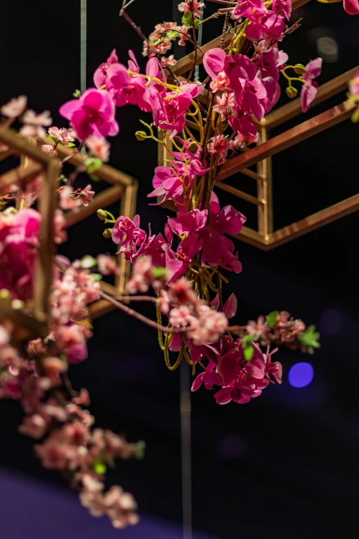 some pink flowers in a purple vase sitting on a stand