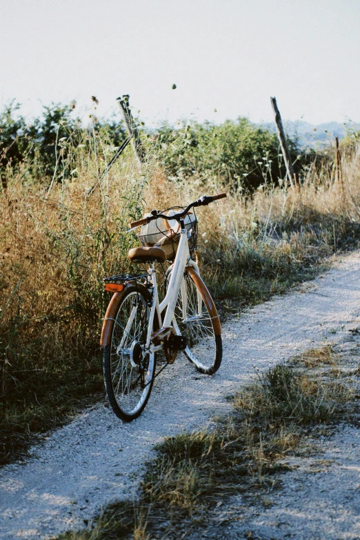 a white bike parked on top of a dirt road