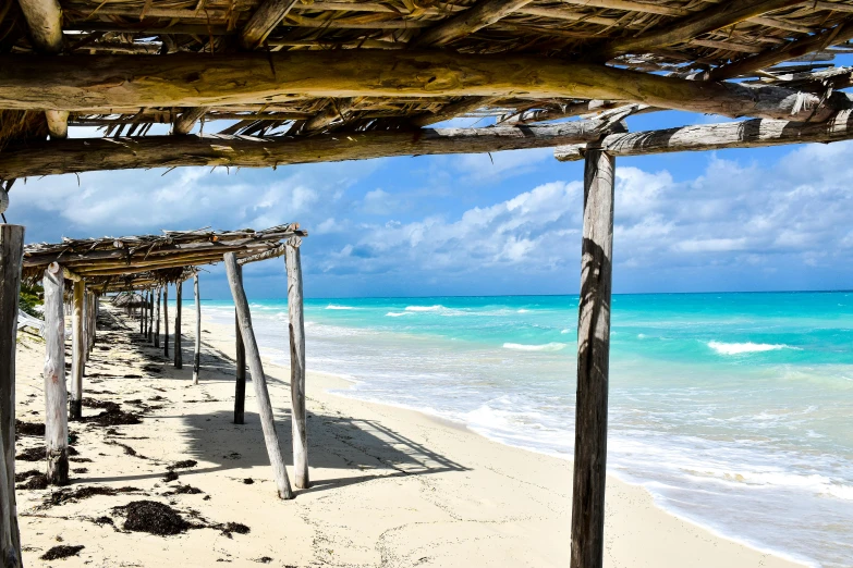 a beach with water in the background and a wooden structure on the sand