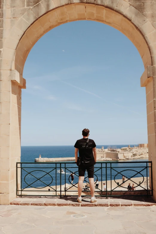 a man looking out over the ocean from a gate