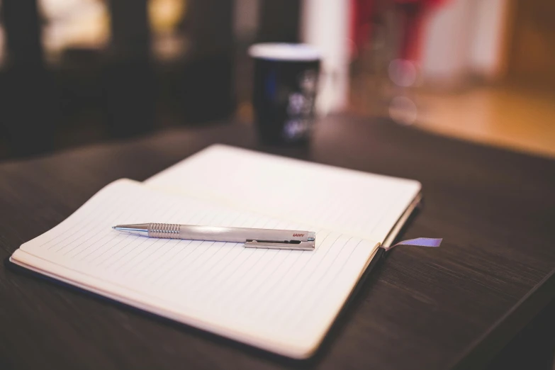 a notebook and pen sitting on a wooden table