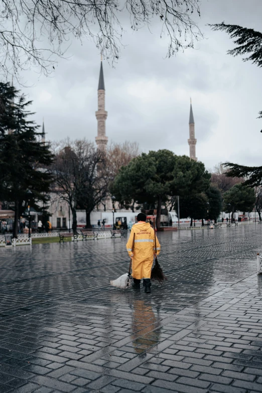 a person with yellow coat and a umbrella walking in the rain
