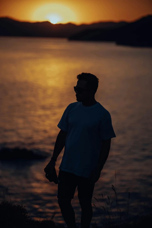 man standing in front of sunset overlooking body of water