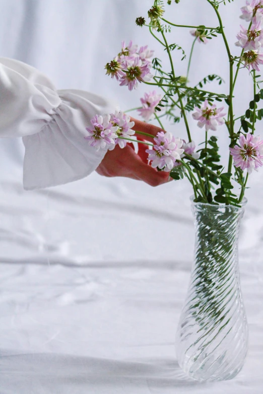 a vase of flowers being held by a woman's hand