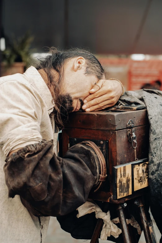 a man with a beard resting his head on top of a stool