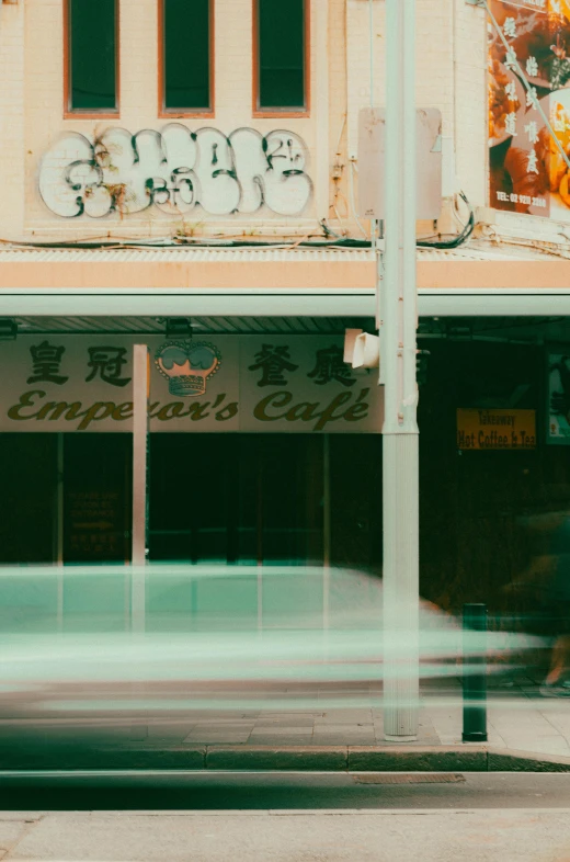 the cars drive by an old store with graffiti