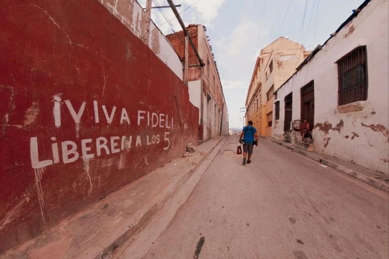 a man riding a bike on a street next to a large red wall