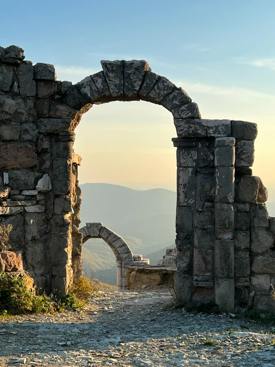 a large arch between two buildings with a mountain in the background