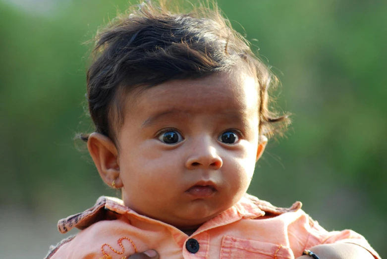 a baby with dark brown hair staring ahead