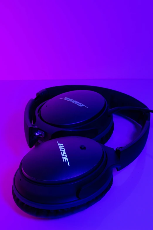 two blue headphones sit on top of a purple background