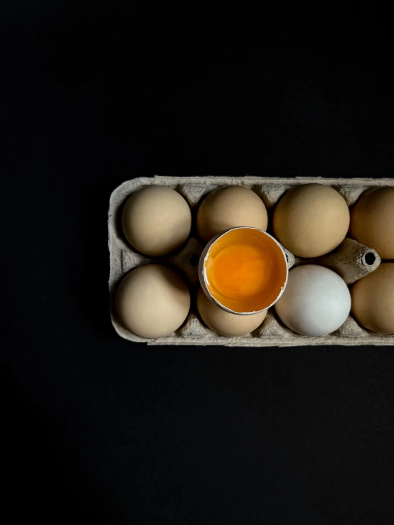 a carton full of eggs and one empty egg cup