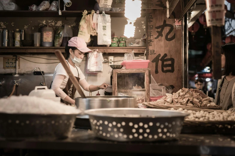 a woman cooking inside a kitchen surrounded by pots and pans