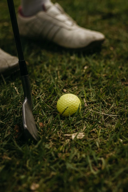 a person with their foot on a golf ball on the grass