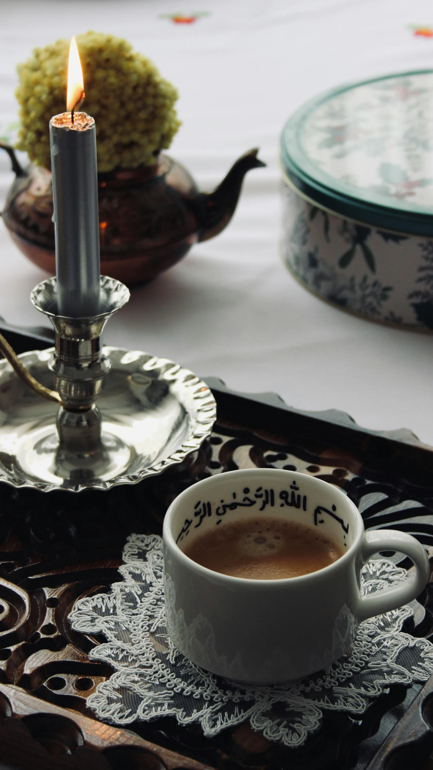 an ornate tray holding a candle and a coffee cup