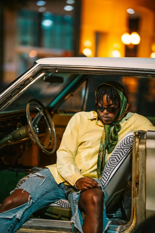 man sitting inside a car wearing a yellow shirt