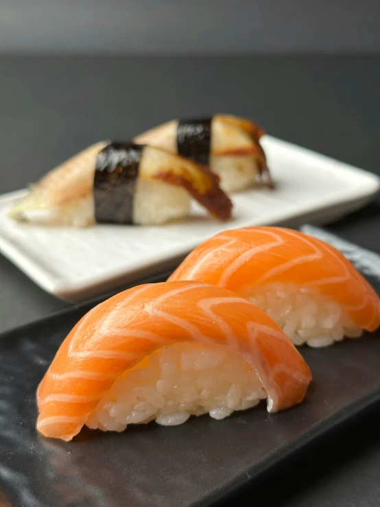 two sushi pieces on plates on top of a table