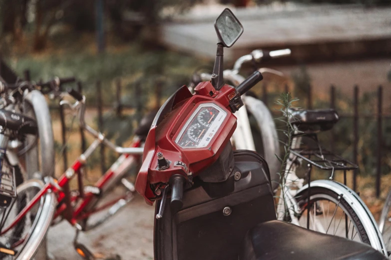 red scooter parked near many bikes in a parking lot