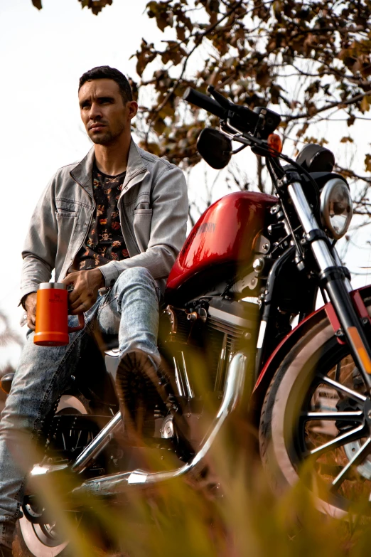 a man sitting on a motorcycle holding a cup