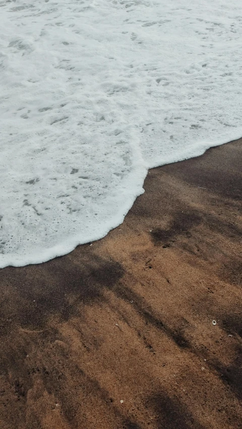 waves crashing in on the beach with brown sand