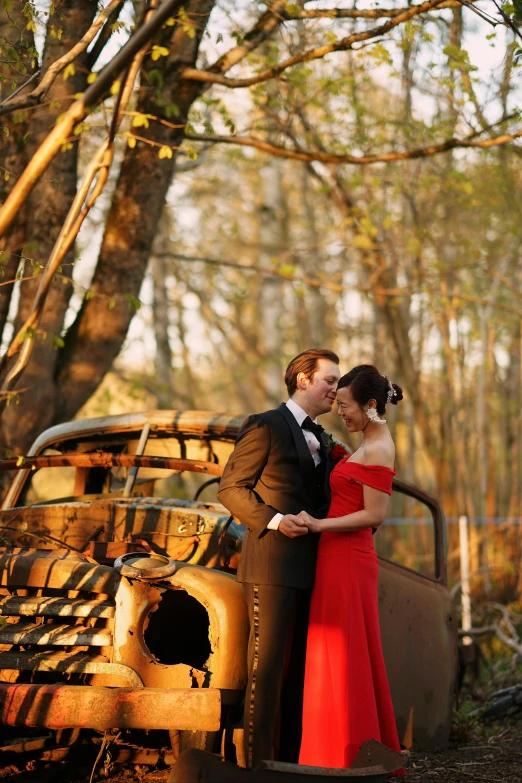 a woman and a man are dressed formally by an old truck