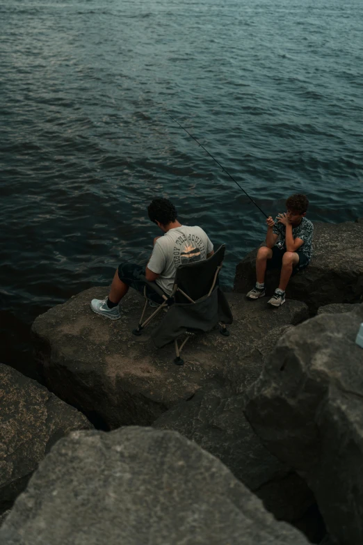 two people sitting on the edge of a body of water