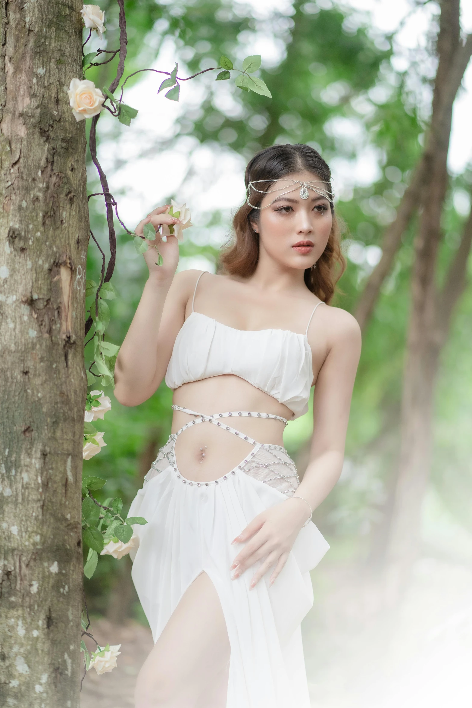 a woman wearing white poses against a tree