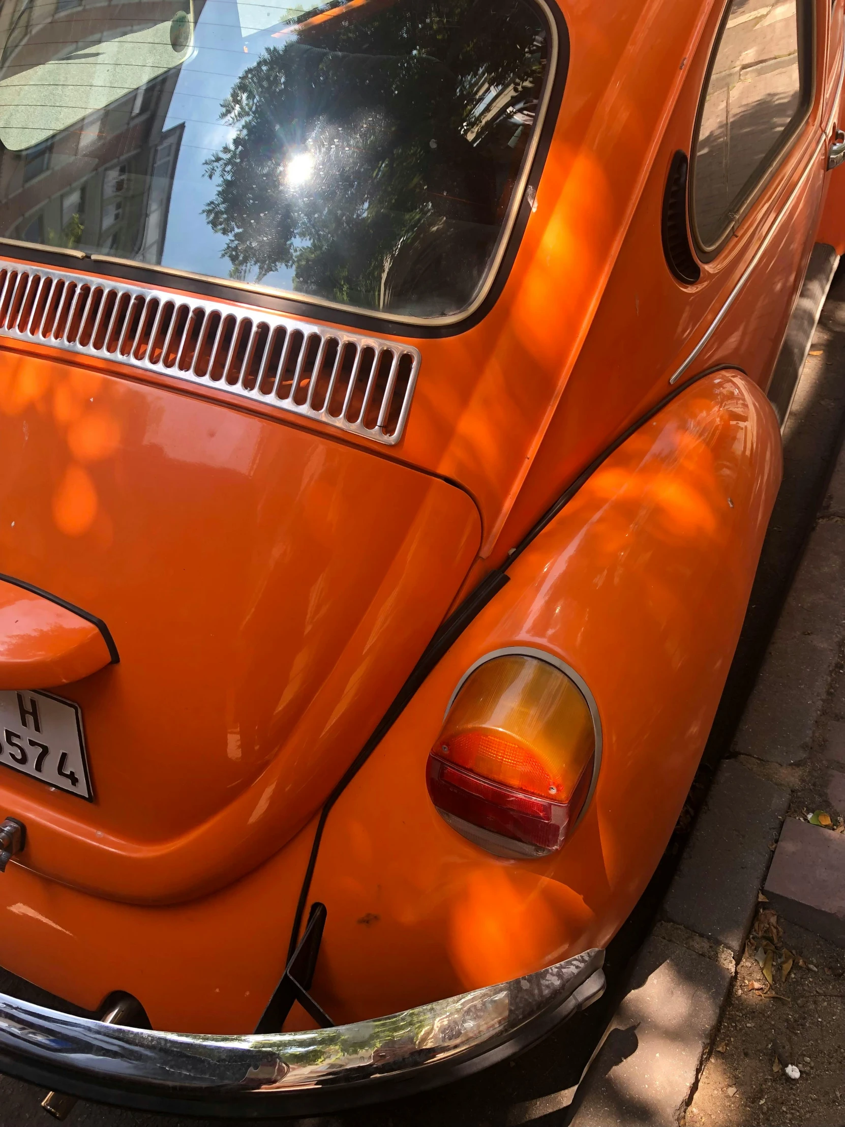 an old vw bug is orange as it sits next to another vw beetle