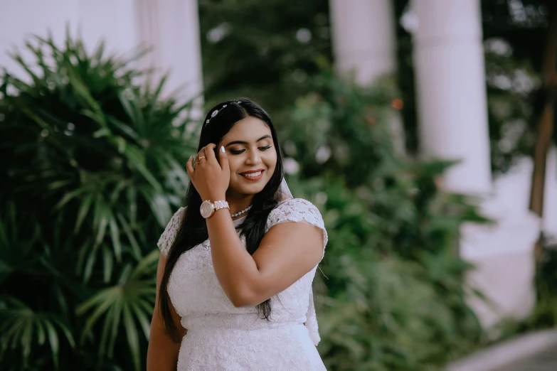 a woman wearing a white dress is smiling and making a call on her phone