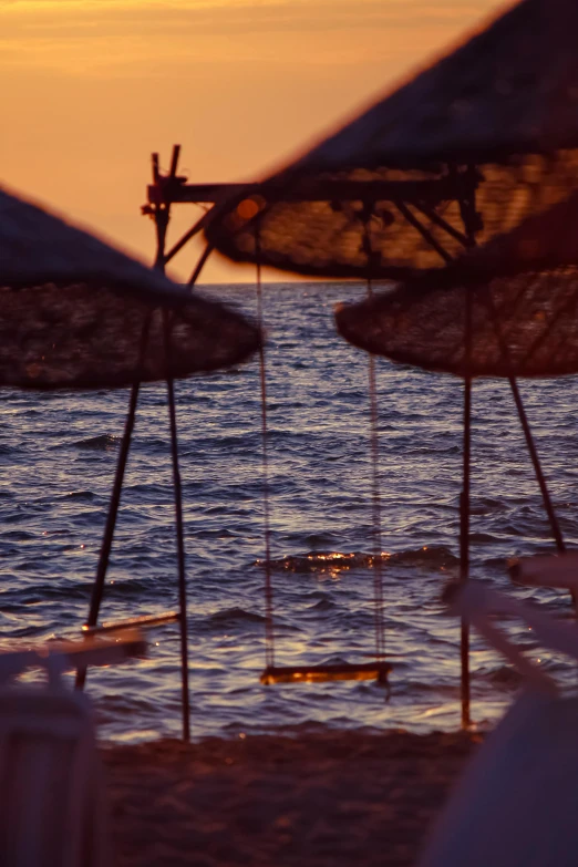 umbrellas on beach next to ocean with setting sun