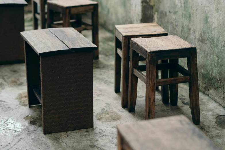 five wooden stools sitting in front of an empty wall