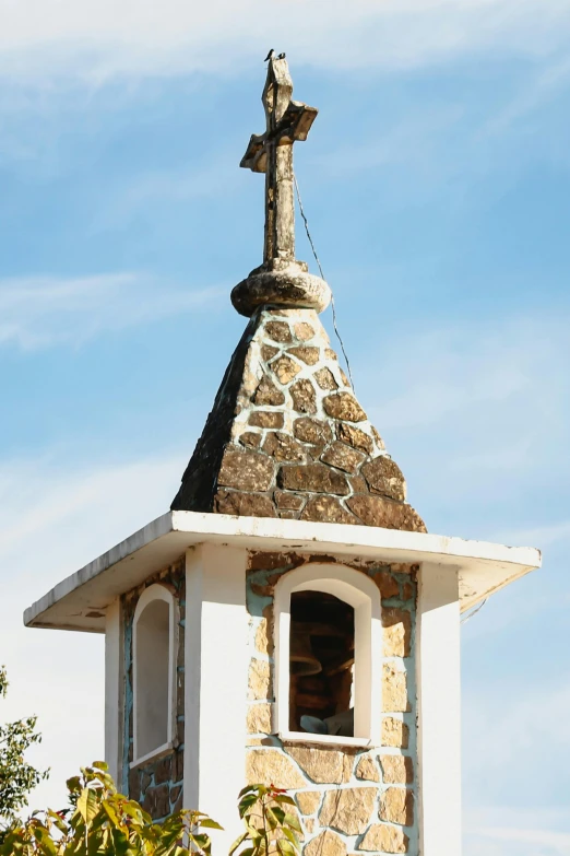 a small church with a stone cross on the top