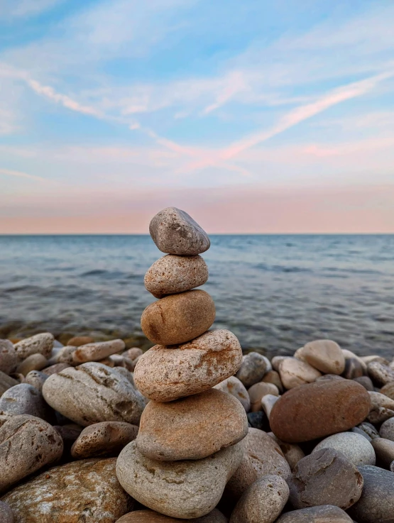 several rocks stacked up on the shore with the ocean in the background