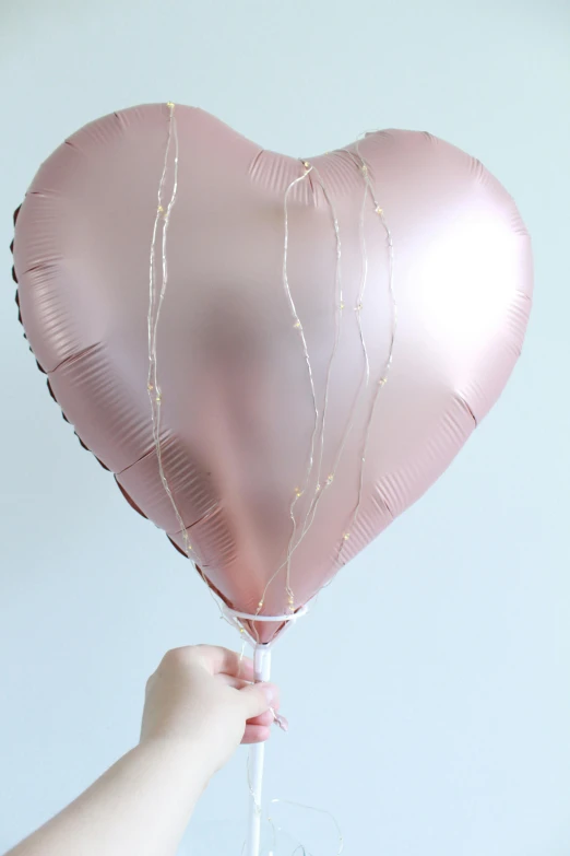 a pink heart shaped balloon being held up by a hand