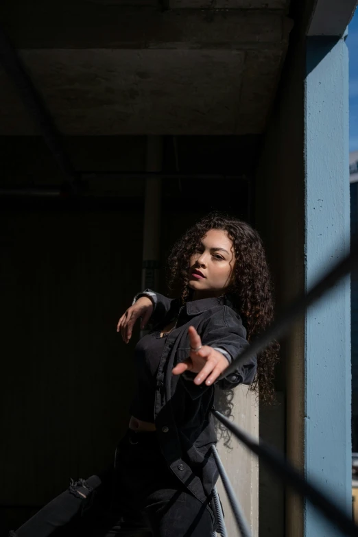 a woman wearing black poses near a metal object