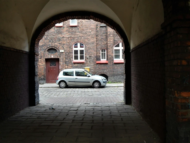 an automobile is seen through an arch in a building