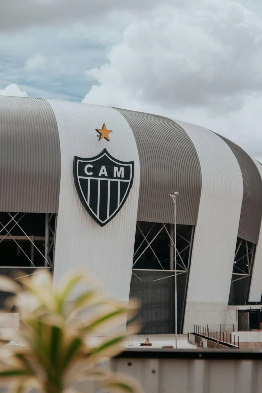 the large white stadium building has a large black emblem on it's side