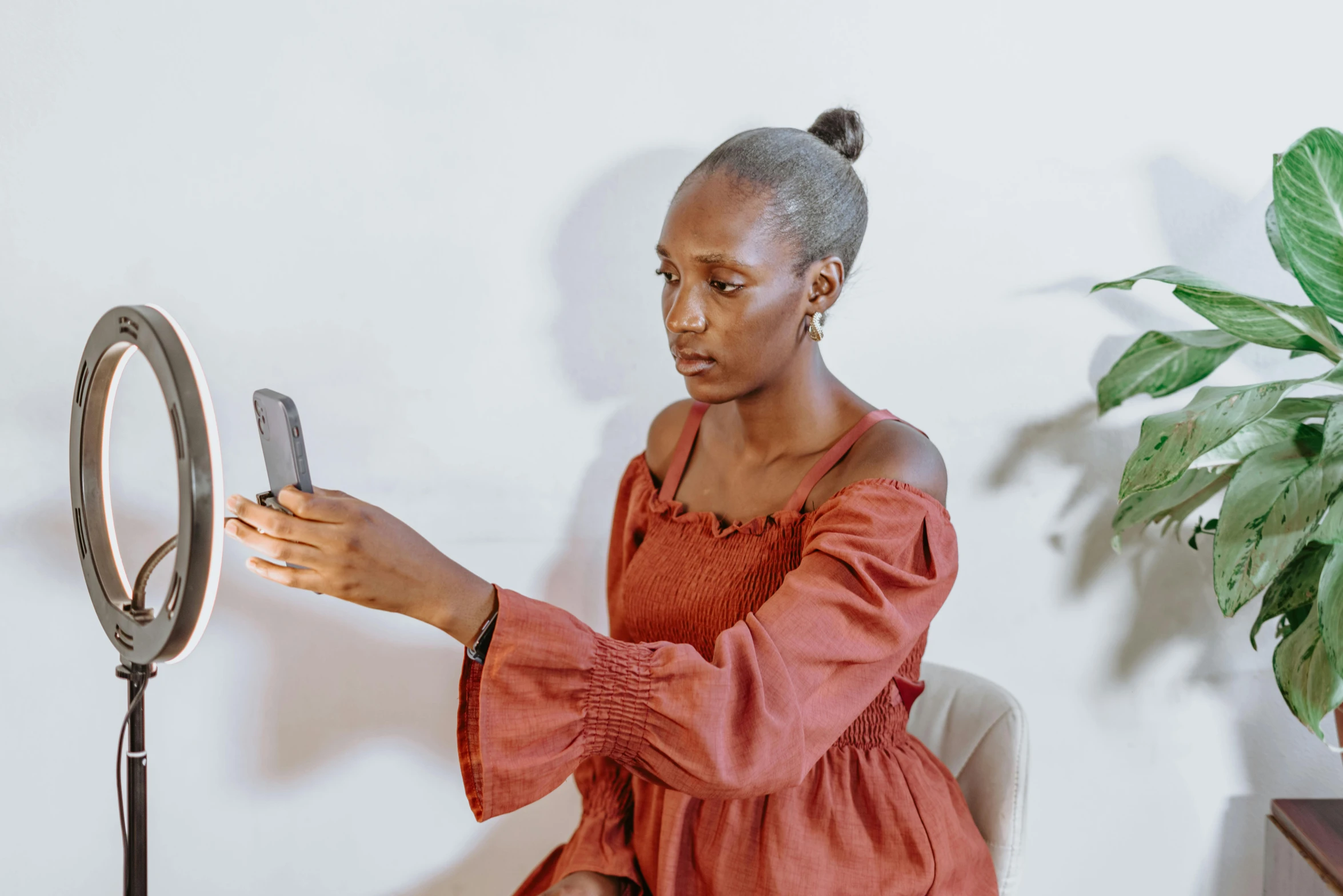 woman holding phone while looking at it in mirror