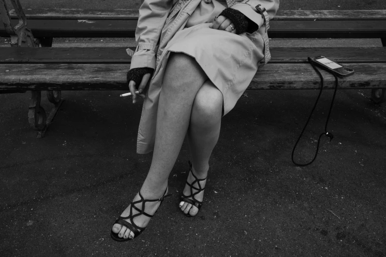 black and white po of a woman wearing high heels sitting on a bench