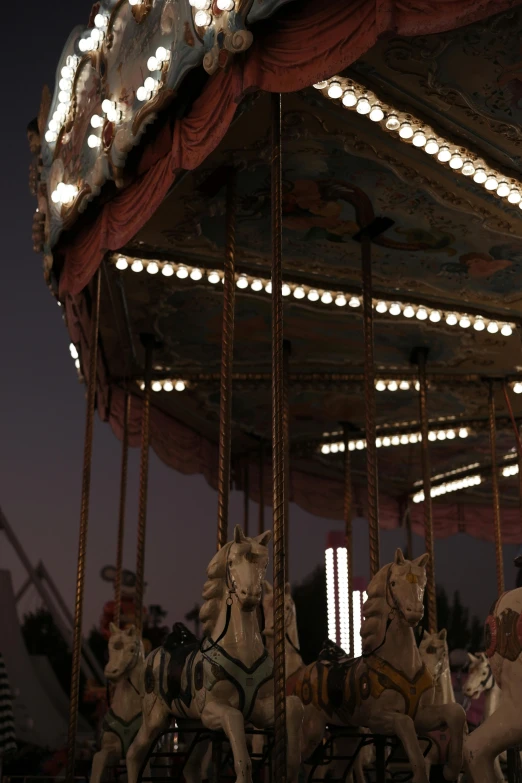 three white horse rides in front of a decorated carousel