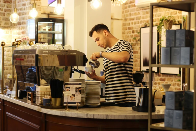 a man pouring coffee at the counter of a cafe