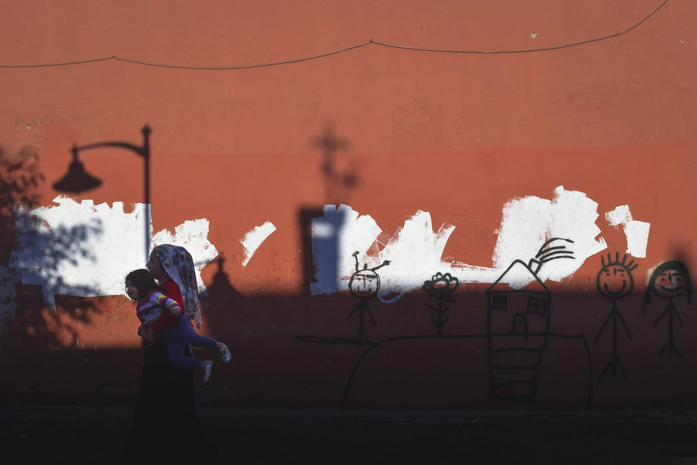 a woman walking past a red wall with writing