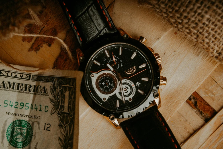 an analog watch with a dollar bill on the table