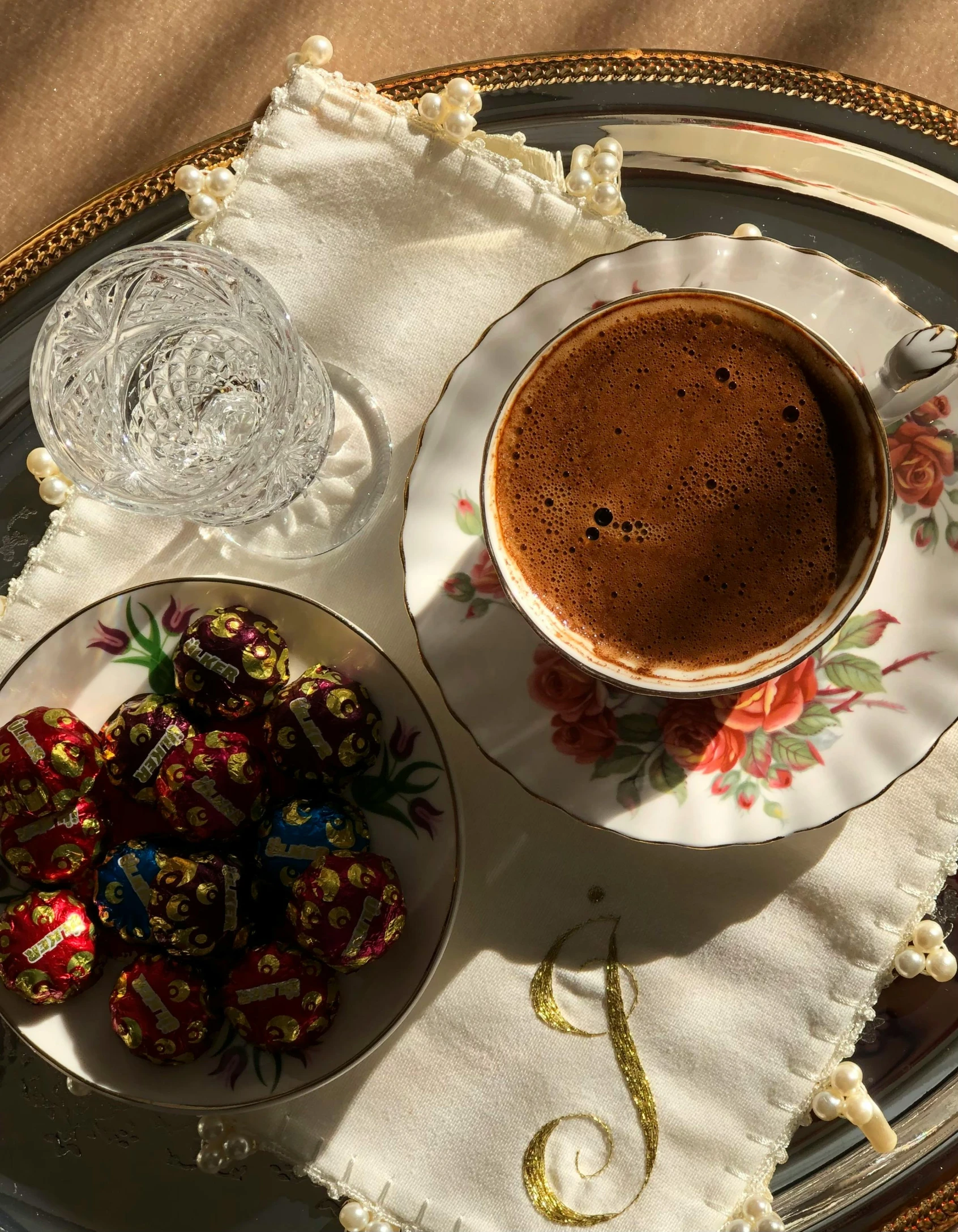 a white plate topped with a cup of chocolate next to other pieces of food