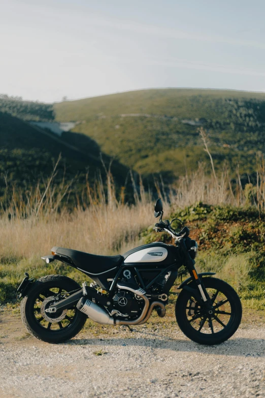 a motorcycle parked on a dirt road near mountains