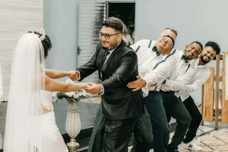 two brides and a groom are shaking hands together