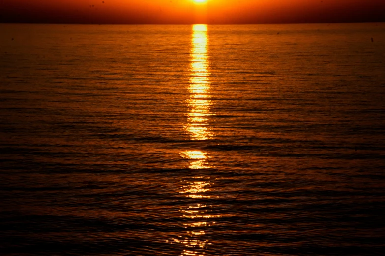 the sun is setting over water at the ocean