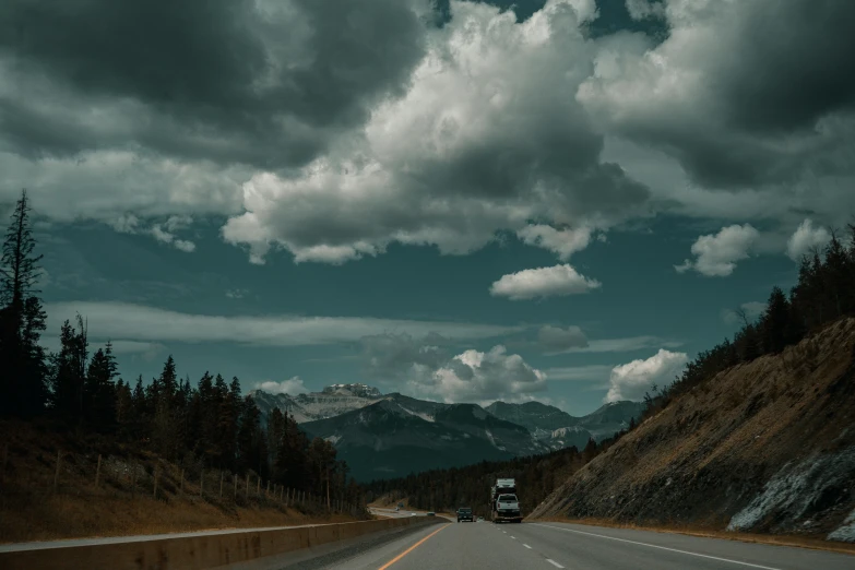 the truck is driving down the road towards some mountains