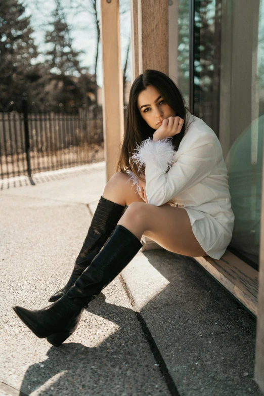 woman in white coat and black boots on the curb