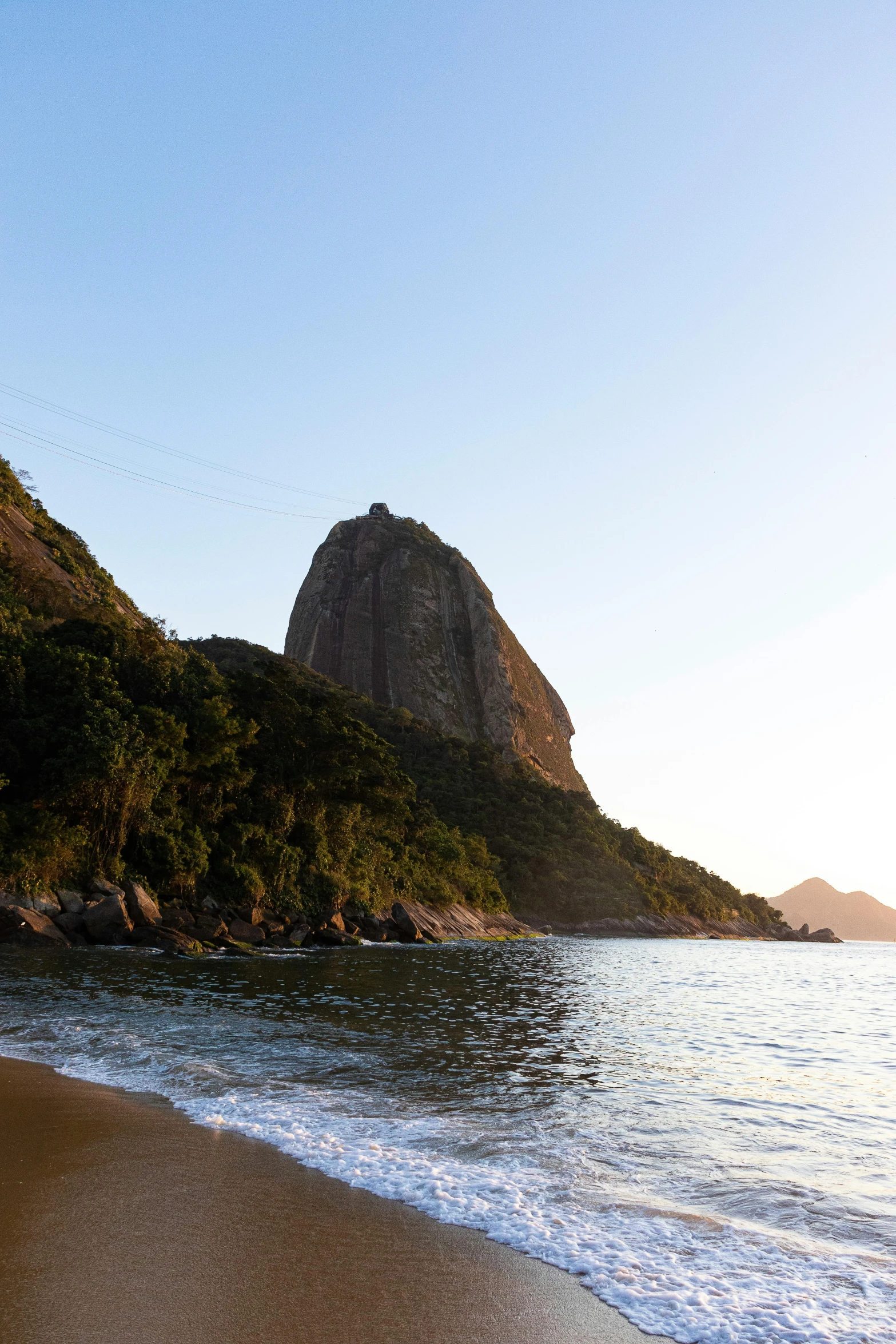 a rocky beach with some water and a hill in the distance