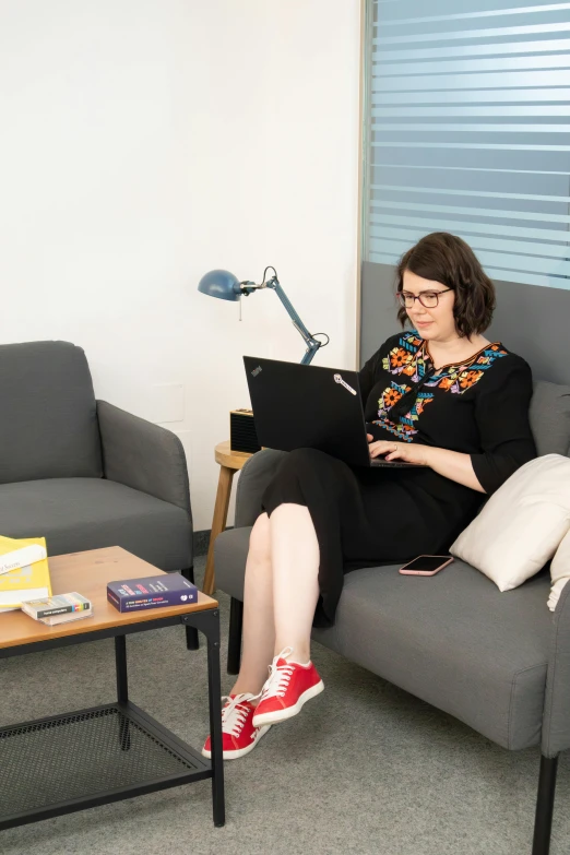 a woman sits in a chair with her laptop on